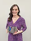 Woman in purple dress holding an award plaque.