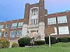 Historic school building with a bell and sign.
