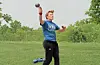 Athlete throwing a shot put in a grassy field.