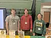Three students at a table with event flyers.