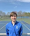 Young male tennis player in blue jacket on a tennis court.