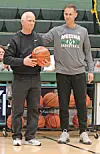 Two coaches with a basketball on a gym court.