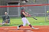 Youth softball player swinging a bat with a ball in the air.