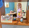 Child holding a toy ice cream cone in a playset.