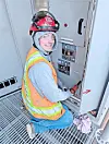 Technician in safety gear working on an electrical panel.