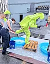 Responders in yellow suits practice decontamination steps.