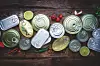 Various cans and fresh ingredients on a wooden surface.
