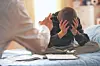 Child with head in hands on a bed during a serious conversation.