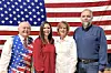 Four people stand in front of an American flag.