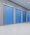 Interior of a storage facility with blue roll-up doors.