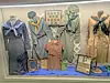 Display of historical uniforms in a showcase.
