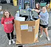 Students next to a box of electronic waste at a recycling event.