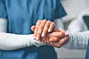 Healthcare worker holding a patient's hand.