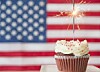 Cupcake with sparkler in front of an American flag.