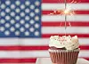 Cupcake with sparkler in front of an American flag.