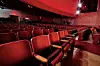 Interior of a theater with red seats and stage lights.
