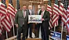 Two men holding a campaign sign with American flags in the background.