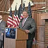 Speaker at a podium with American flags in the background.