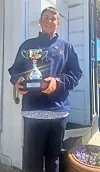 Young athlete holding a trophy outside a building.