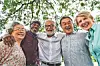 Group of smiling friends gathered under a tree.