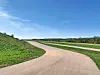 Curved road in a green landscape with blue sky.