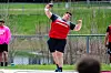 Athlete in red jersey throwing shot put at a competition.