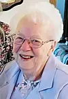 Elderly woman smiling in a light blue jacket.