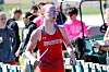 Runner in red uniform with baton at a track event.