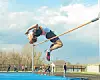 Athlete jumping over a high jump bar at a track event.