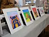 Colorful animal portraits displayed on a table at an art event.
