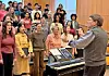 Conductor leading a choir rehearsal in an auditorium.
