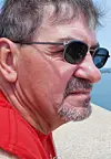 Profile of a man in sunglasses by the water.