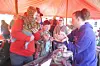 Families engaging at a community event under a red tent.