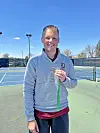 Tennis coach holding a medal on the court.