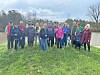 Group of people standing on grass near water.