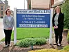 Two women standing next to a law office sign.
