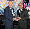 Two men holding an award at a formal event.