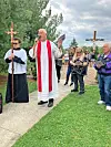Clergy leading an outdoor memorial service with attendees.