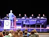 A speaker in a suit stands before judges in a mock trial.