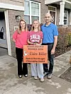 Claire Miller with her parents holding a scholarship award sign.