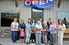 Group holding oversized scissors at a business grand opening.