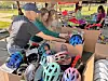 Volunteers help children choose helmets from boxes.