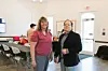Two individuals stand in a community center during a networking event.