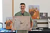 Young artist holds a wildlife photograph at an exhibition.