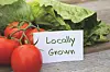 Fresh tomatoes and lettuce with a locally grown sign.