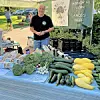 Farmer at a market with vegetables and meats on display.