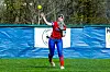 Player catching a softball in a red and blue uniform.