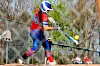 Player in red and blue uniform swinging at a softball.