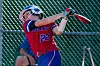 Young athlete swinging a bat in a softball game.