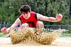 Athlete jumping into sand pit during long jump.